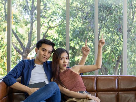 Young couples spend holidays in the living room. The young man wore comfortable clothes and the girlfriend pointed finger in the same direction.