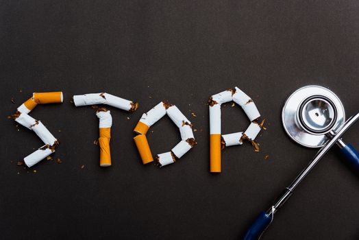 31 May of World No Tobacco Day, no smoking close up word STOP spelled text of the pile cigarette or tobacco and doctor stethoscope on black background with copy space, and Warning lung health concept