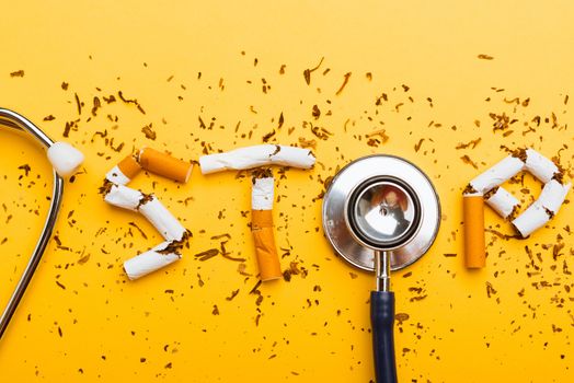 31 May of World No Tobacco Day, no smoking close up word STOP spelled text of the pile cigarette or tobacco and doctor stethoscope on yellow background with copy space, and Warning lung health concept