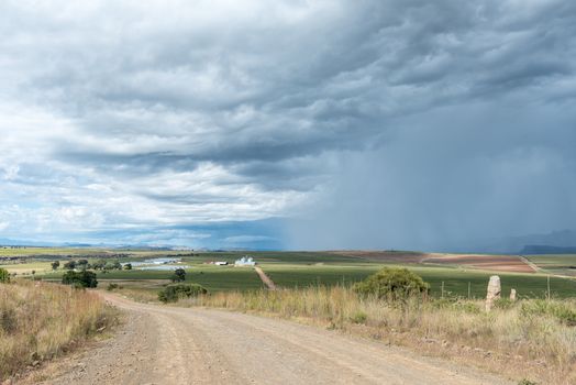 Gravel road landscape near Fouriesburg. The Bloukruin Manitoba farm and a thunderstorm are visible