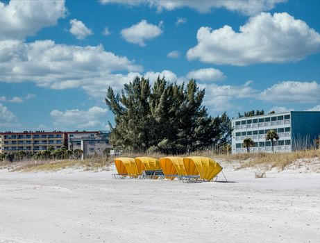 Blue chaise lounges on a beach under yellow sun shades