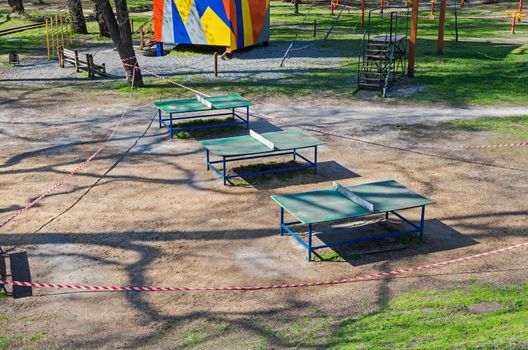 Sports playground with tennis tables in old city park is fenced with barricade tape during COVID-19 coronavirus infection pandemic. It is forbidden to be in public places during quarantine