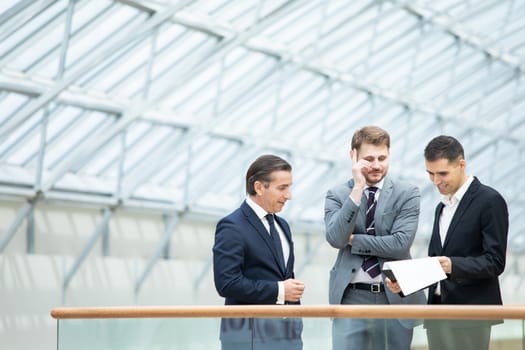 Business people having informal meeting in modern office discussing documents