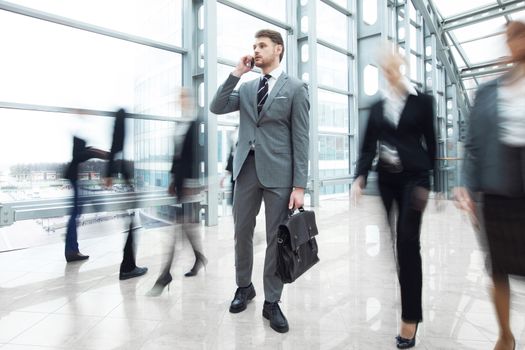 Business man talking on phone standing in a crowd of walking people