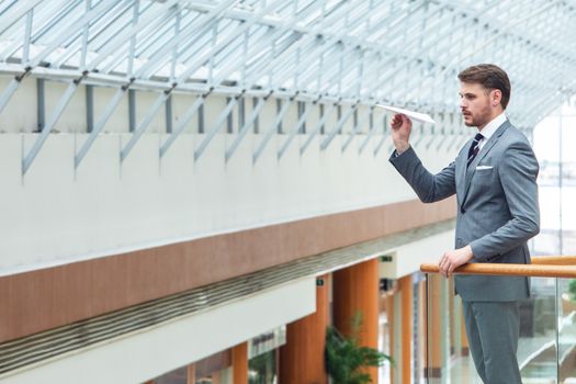 Young business man throwing a paper plane in office building