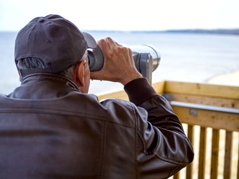 man looking through tourist binoculars. Hands on the telescope. ocean on the background. vacation concept