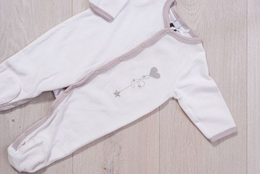 baby clothes concept. white and gray suit for boy and girl on wooden background