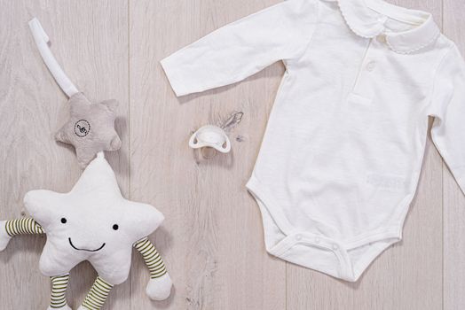 baby clothes concept. white suit for boy and girl and a baby pacifier on wooden background