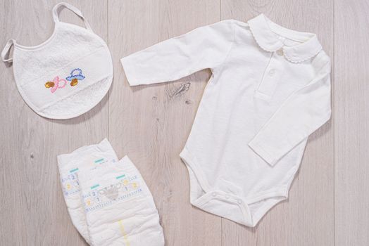 White baby clothes, diapers and baby bib. newborn