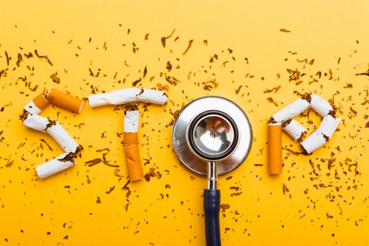 31 May of World No Tobacco Day, no smoking close up word STOP spelled text of the pile cigarette or tobacco and doctor stethoscope on yellow background with copy space, and Warning lung health concept