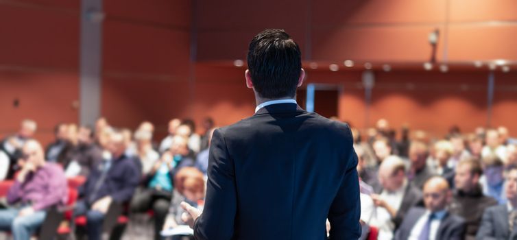 Speaker giving a talk on corporate business conference. Unrecognizable people in audience at conference hall. Business and Entrepreneurship event.