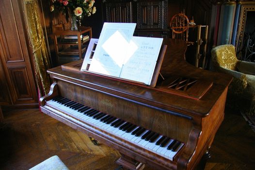 Antique piano in a room with period furniture on a wooden floor