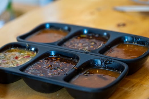 The Spicy sauces and condiments for Shabu in cup of sauce on a wooden table background.dipping sauce for shabu.