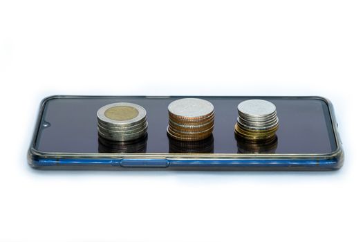 stack of coins on smart phone isolated on white background - business finance concept