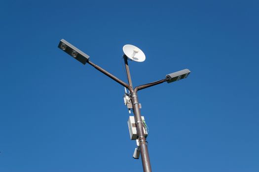 Lamppost with an antenna mounted on it. Pillar against the blue sky.