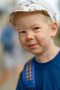 Portrait of a smiling boy in a blue T-shirt and a light cap.