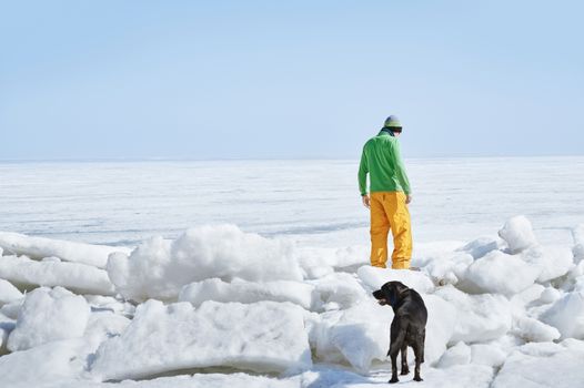 Young adult man outdoors with his dog exploring winter landscape