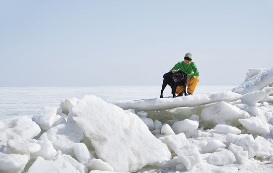 Young adult man outdoors with his dog having fun in winter landscape