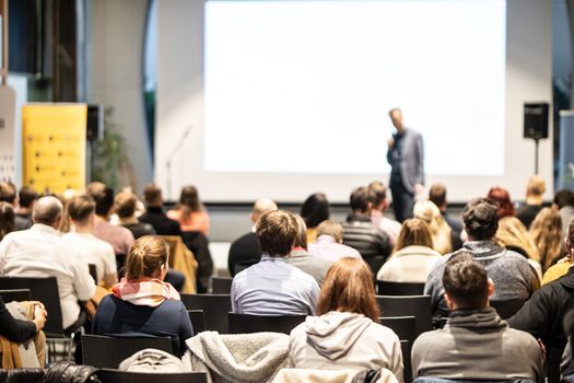 Speaker giving a talk in conference hall at business event. Rear view of unrecognizable people in audience at the conference hall. Business and Entrepreneurship concept.