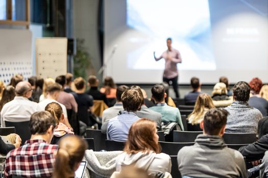 Speaker giving a talk in conference hall at business event. Rear view of unrecognizable people in audience at the conference hall. Business and entrepreneurship concept.