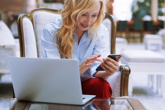 Businesswoman using smartphone in the modern bank lobby