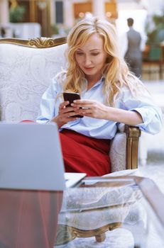 Businesswoman using smartphone in the modern bank lobby