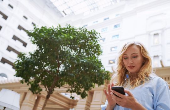 Businesswoman using smartphone in the modern bank lobby