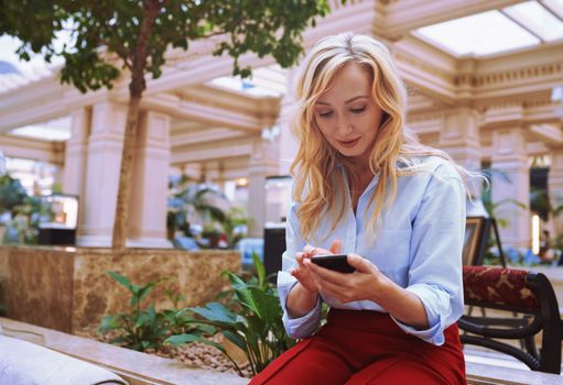 Businesswoman using smartphone in the modern bank lobby