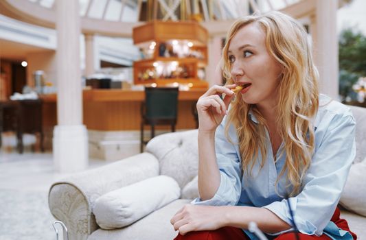 Woman enjoying snack and sitting at the hotel lobby