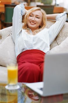 Woman relaxing in the hotel lobby and blogging via laptop