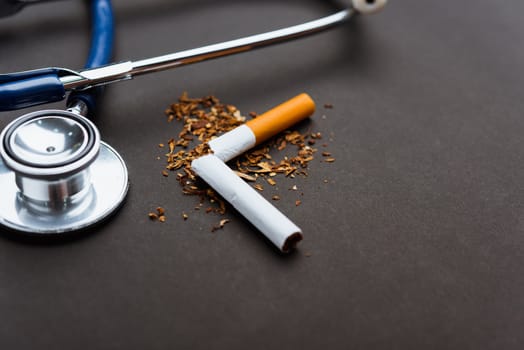 31 May of World No Tobacco Day, no smoking, close up of broken pile cigarette or tobacco and doctor stethoscope on black background with copy space, and Warning lung health concept