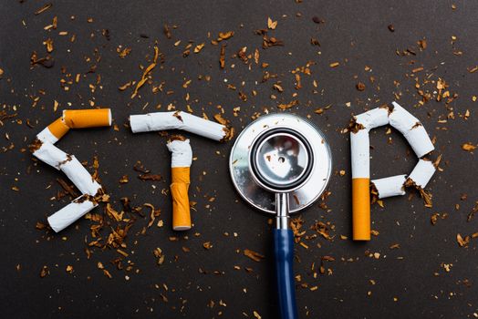 31 May of World No Tobacco Day, no smoking close up word STOP spelled text of the pile cigarette or tobacco and doctor stethoscope on black background with copy space, and Warning lung health concept