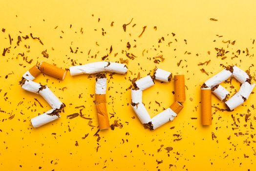 31 May of World No Tobacco Day, no smoking close up word STOP spelled text of the pile cigarette or tobacco on yellow background with copy space, and Warning lung health concept