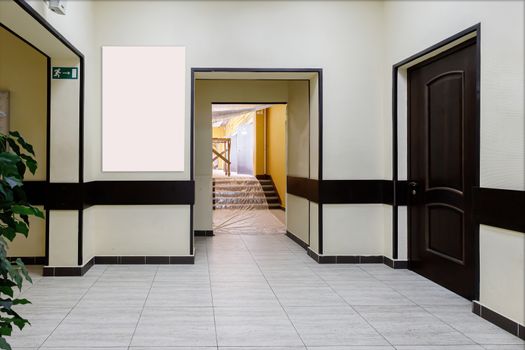 An empty corridor in a modern office building. A hall with light walls and brown doors.