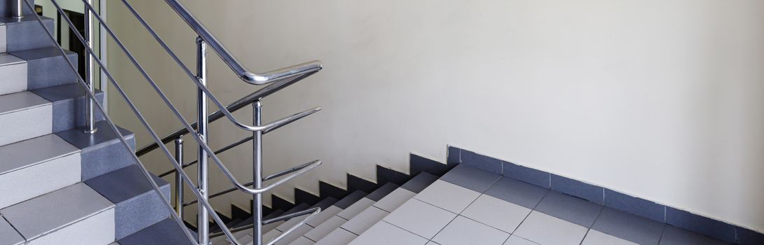 The concept of the interior of an urban building. Photo of a staircase with metal railing between floors.