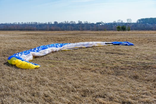 parachute spread on dry grass on the field on a sunny day, preparing for flight