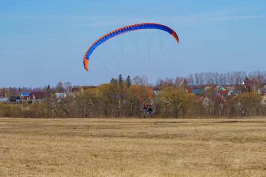 the paraglider begins to take off over the field on a sunny spring day