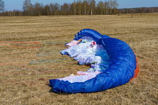 parachute spread on dry grass on the field on a sunny day, preparing for flight
