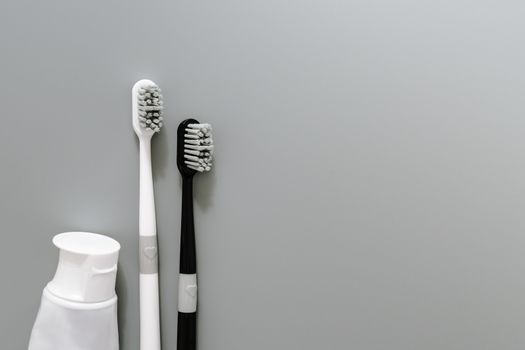 couple of toothbrush with toothpaste on gray background