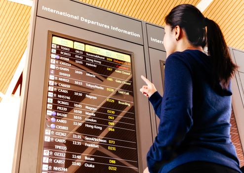 SHANGHAI, CHINA - FEB 2019: woman traveler checking flight schedule in the airport terminal