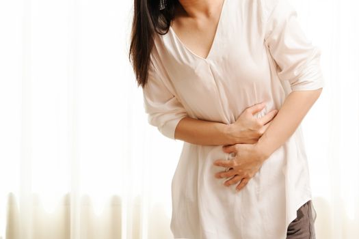 Young woman suffering from abdominal pain feeling stomachache, symptom of pms on white background