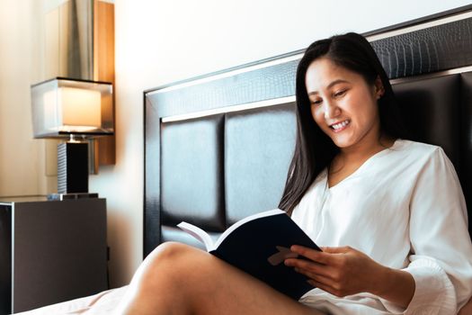 woman sitting on bed reading the book