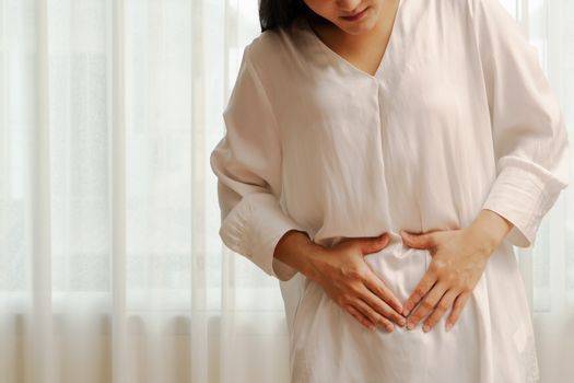 Young woman suffering from abdominal pain feeling stomachache, symptom of pms on white background
