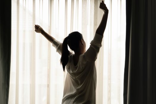 Woman stretching in bedroom after wake up, back view