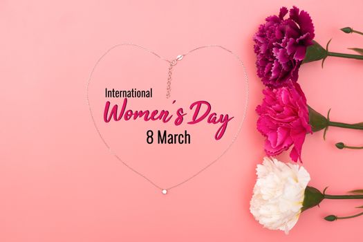 International Womens Day with flowers and heart shape necklace on pink background