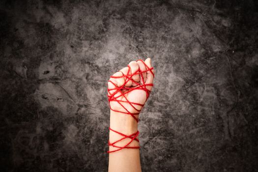 Women hand tied with rope, the idea of freedom expression on dark grunge background in low key. international human rights day concept.