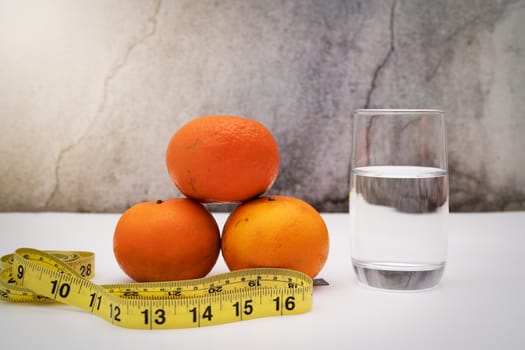 Fresh fruit for diet, measuring tape and drinking water on grunge background. Concept of diet and healthy lifestyle