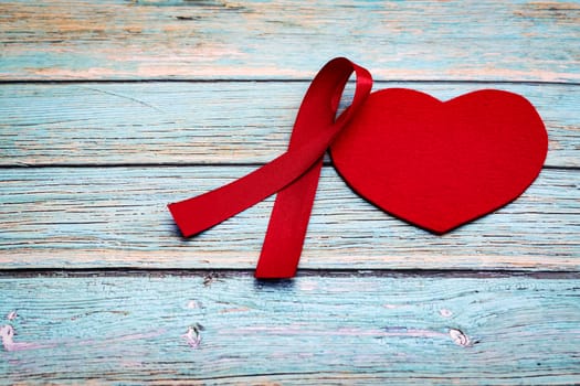 World health day, healthcare and medical concept, red ribbon and red heart on the blue wooden background