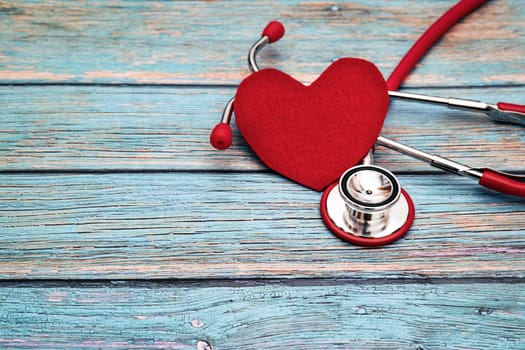 World health day, healthcare and medical concept, red stethoscope and red heart on the blue wooden background