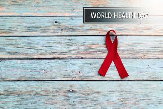 World health day, healthcare and medical concept, red ribbon on the blue wooden background